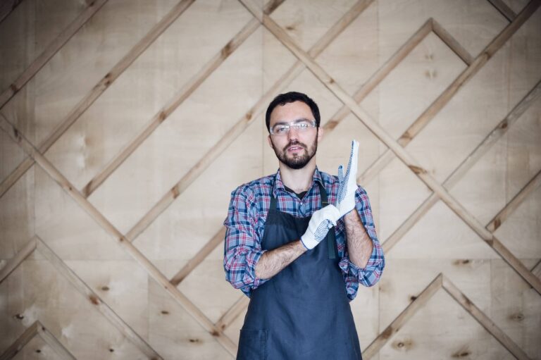 portrait of a carpenter working in workshop wearing gloves