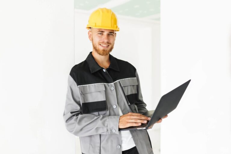young smiling engineer in work clothes and yellow hardhat joyful